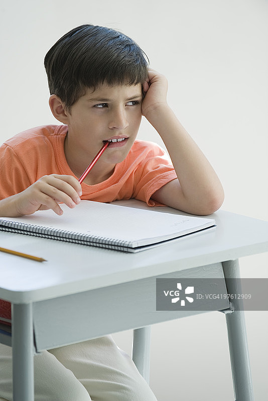 小学生在书桌旁思考图片素材