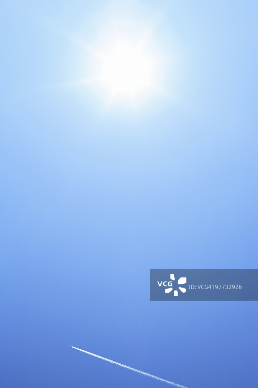 蓝天中的阳光与飞机尾迹图片素材