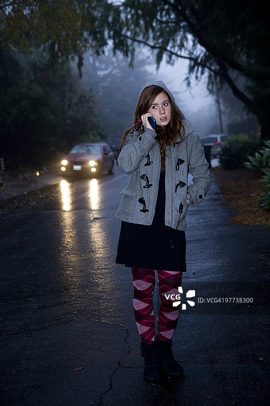 雨中用手机的少女，车辆驶来图片素材
