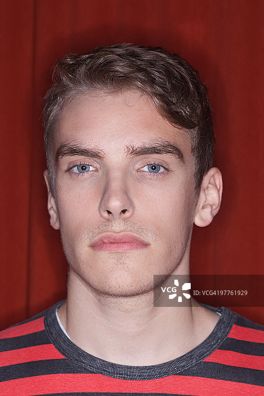 红色背景前的年轻男子肖像图片素材