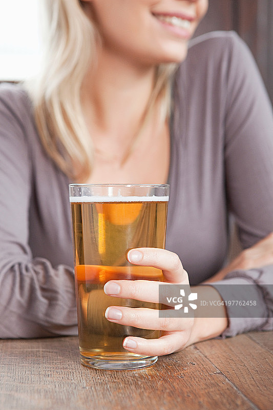 在酒吧里拿着一杯啤酒的年轻女人图片素材