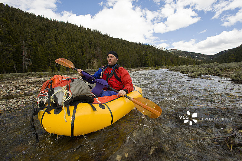 年轻男子在爱达荷州鲑鱼河源头划着小型充气筏图片素材