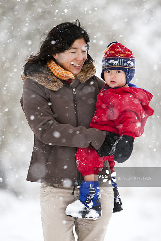 一位母亲在科林斯堡的第一场大雪中和蹒跚学步的儿子玩耍图片素材