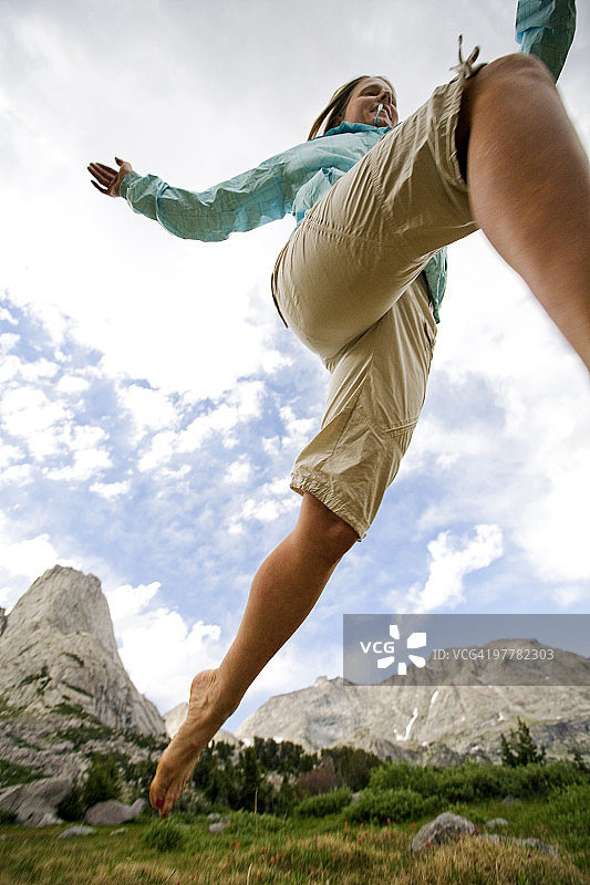 低角度拍摄女子在风河山脉塔群荒野中奔跑图片素材