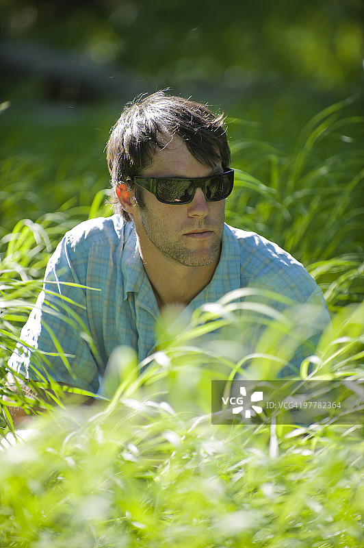 年轻男子坐在长满草的田野里图片素材