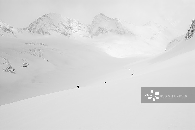 一群滑雪者在山谷中游览，远处是雄伟的加拿大落基山脉图片素材