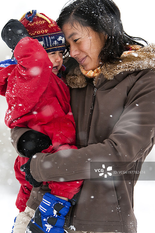 一位母亲在科林斯堡的第一场大雪中和蹒跚学步的儿子玩耍图片素材