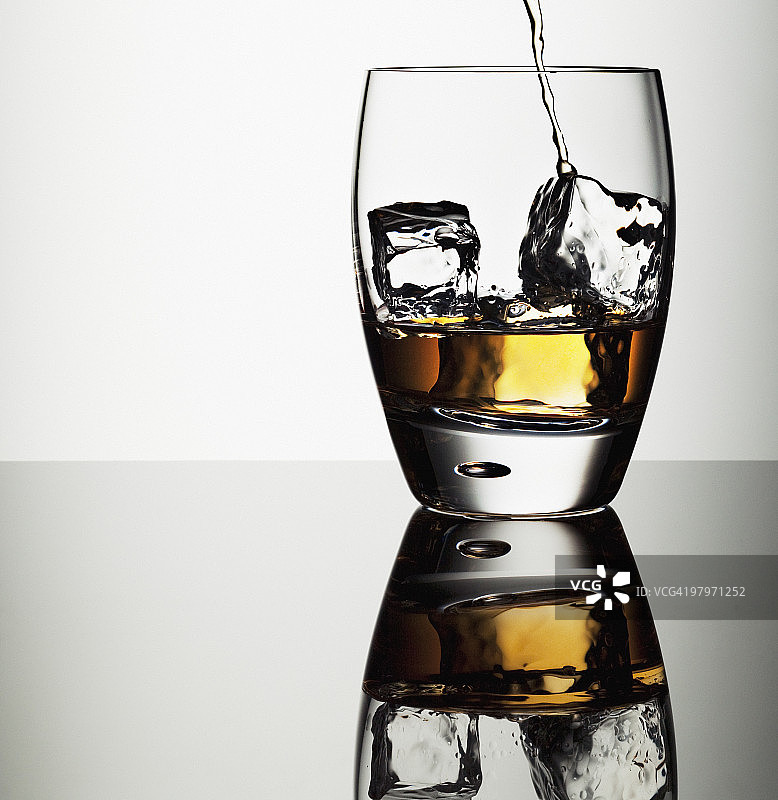酒精倒入含冰块的 Highball 杯中图片素材