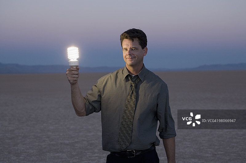 沙漠中拿着灯泡的男人图片素材