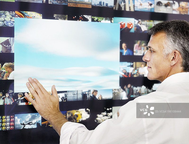 使用数字显示器的灰发男人图片素材