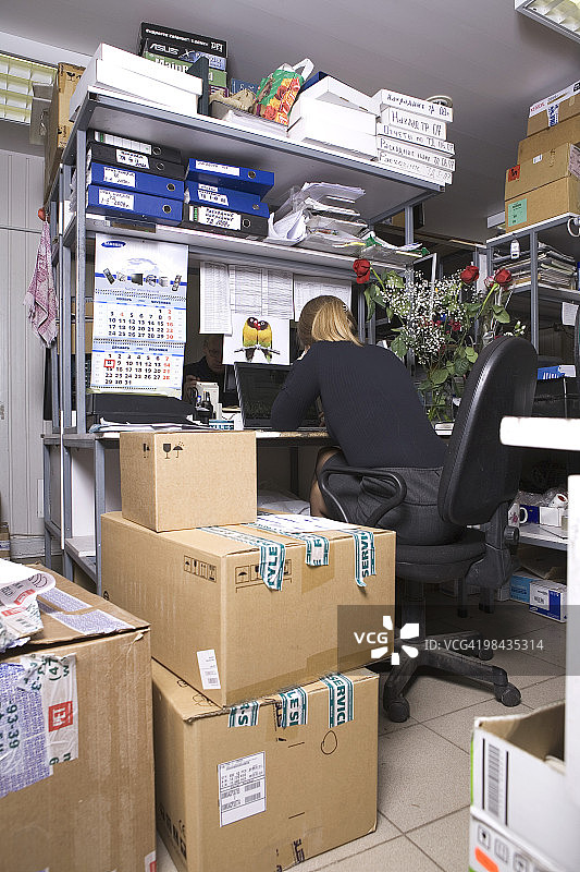 坐在电脑维修店桌前的女人的背面视角图片素材