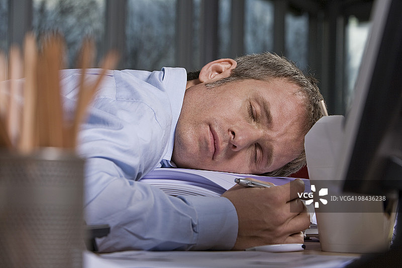 疲惫的商人在办公桌前睡着了图片素材