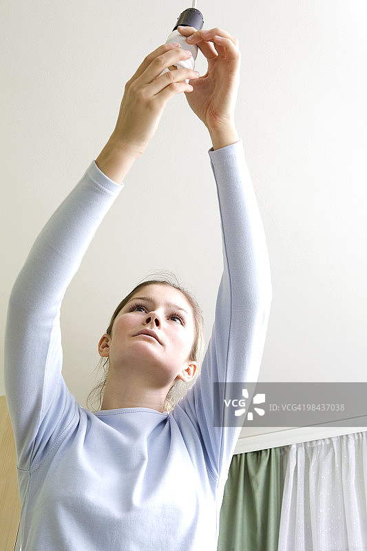 年轻女人更换低能耗灯泡图片素材