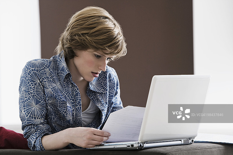 在家阅读文件，使用手提电脑的年轻女人图片素材