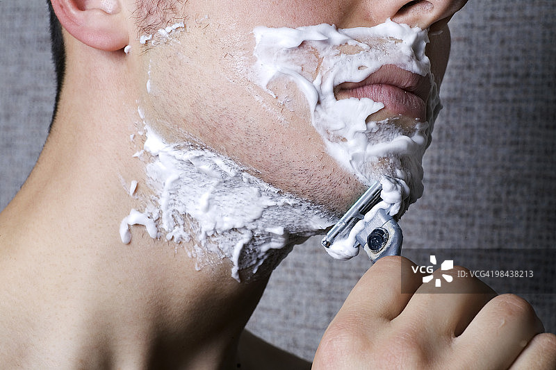 年轻男子刮胡子的特写图片素材