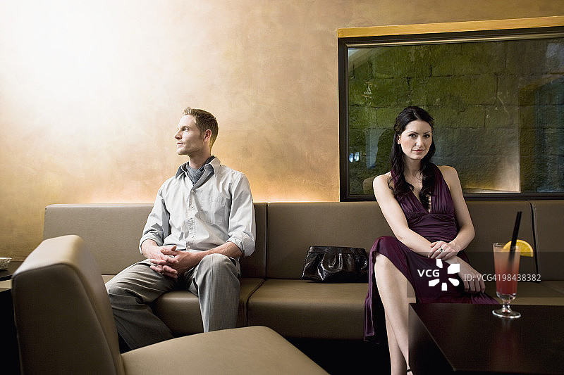 年轻情侣坐在酒吧里，各自看向不同的方向图片素材