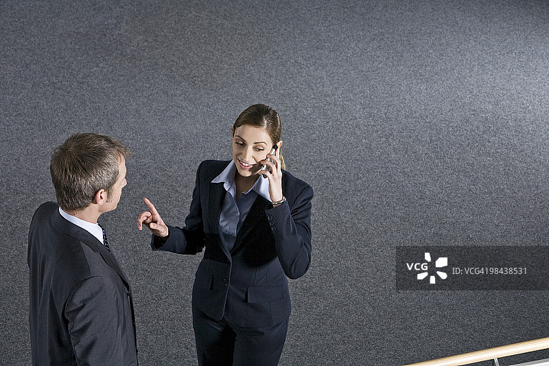 在办公楼里用手机交谈的年轻女人图片素材