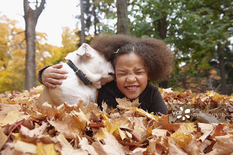 混血女孩和小狗躺在秋叶中图片素材