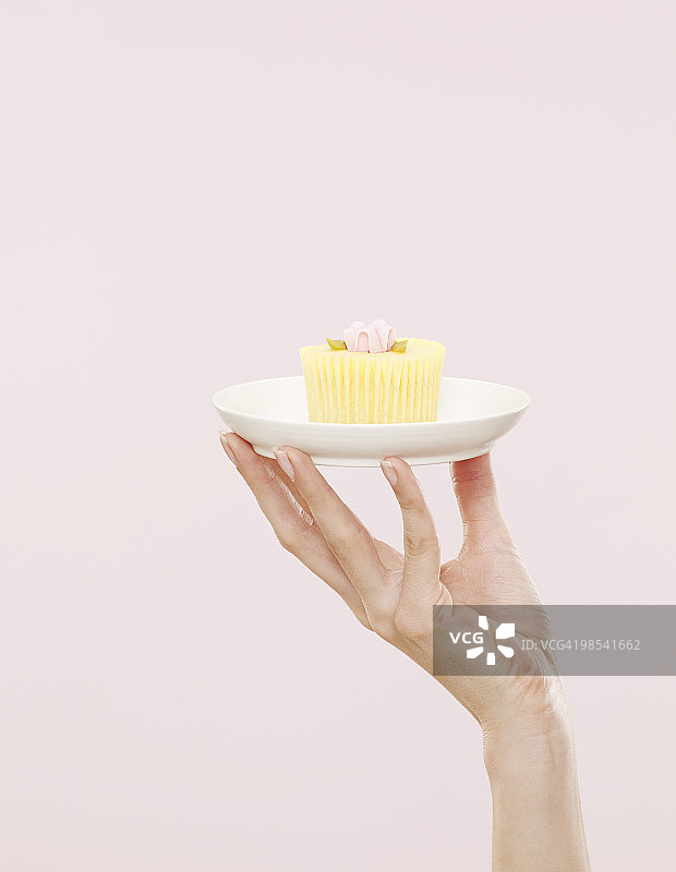 女人手拿白色盘子上的纸杯蛋糕图片素材