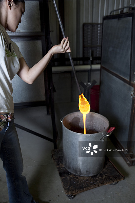 玻璃工匠将热玻璃滴入桶中图片素材