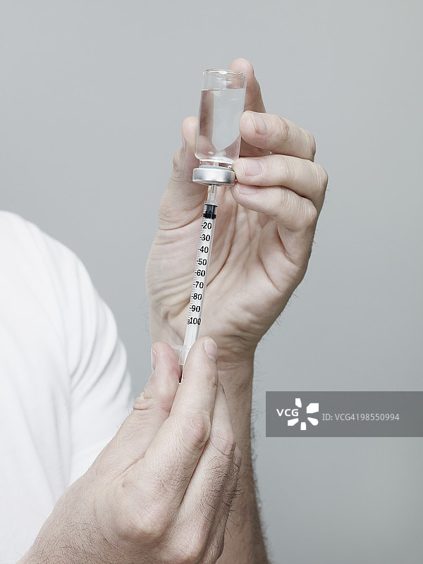 男人从胰岛素瓶中抽取药液到注射器图片素材
