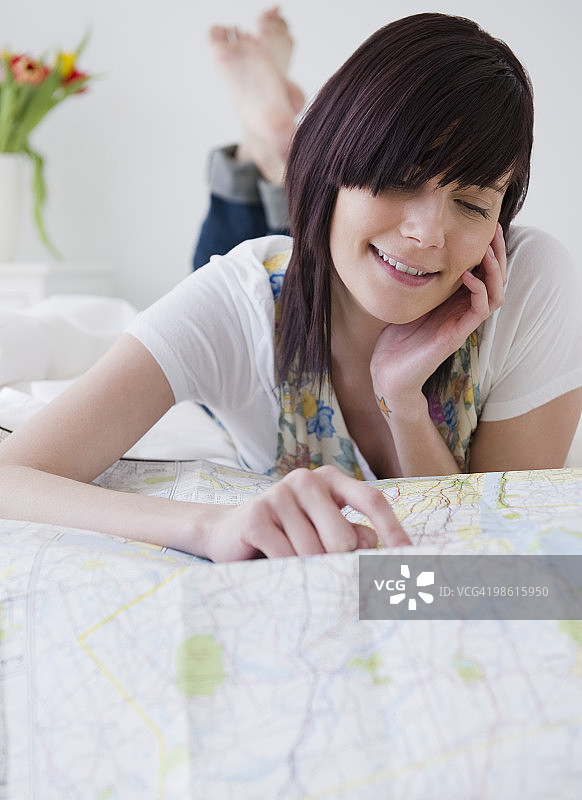 年轻女人指向地图，微笑图片素材