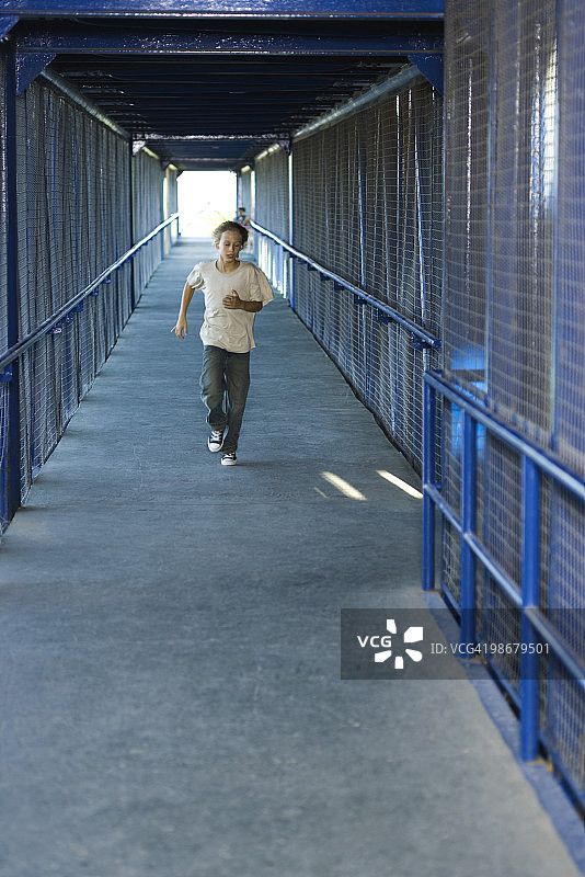 沿着走廊奔跑的青少年男孩（正面视角）图片素材