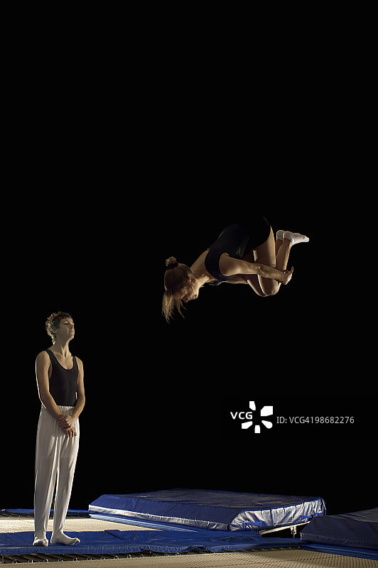 男孩看女孩在蹦床上玩耍图片素材