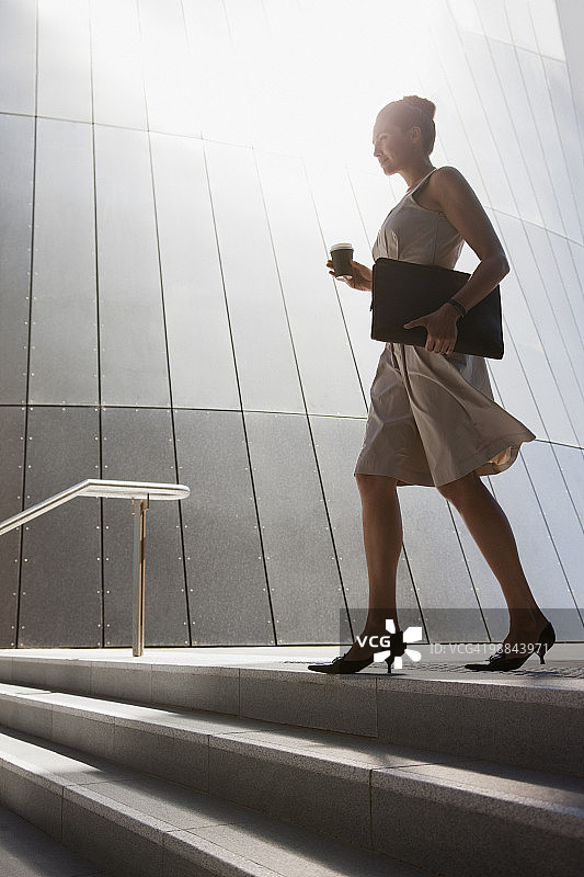 手持咖啡走下户外台阶的女商人图片素材