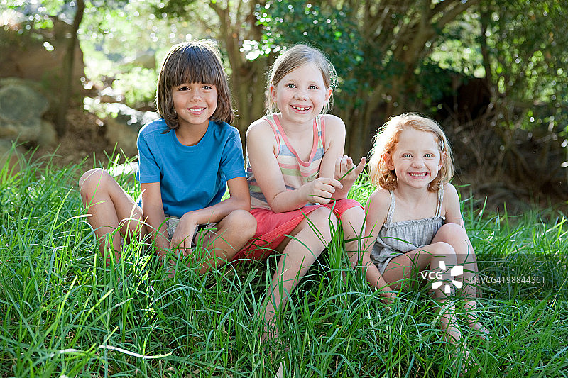 三个孩子坐在草地上图片素材