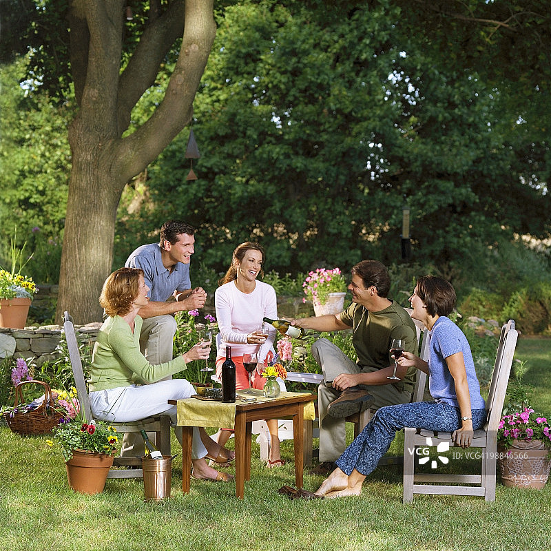 在花园里放松喝酒的五个成年人图片素材