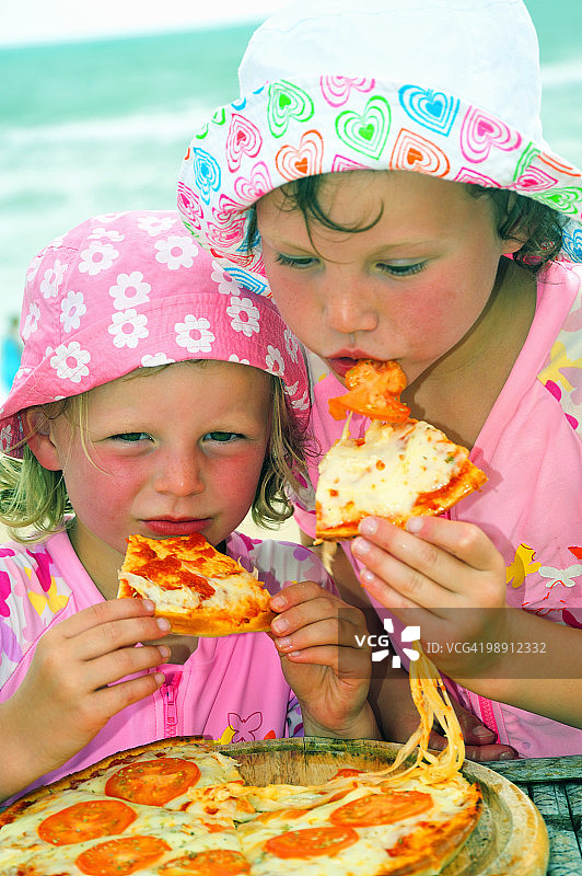 两个孩子（4-5岁）在海滩上吃披萨特写图片素材