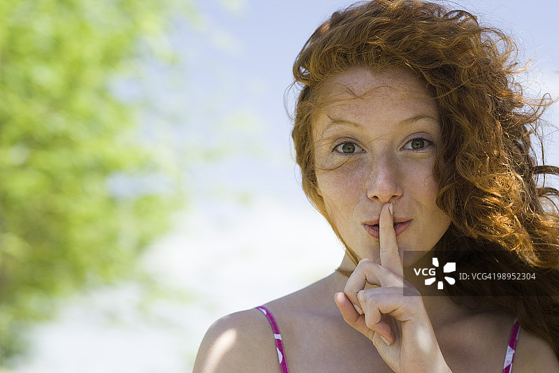 手指放在嘴唇上的年轻女人肖像图片素材