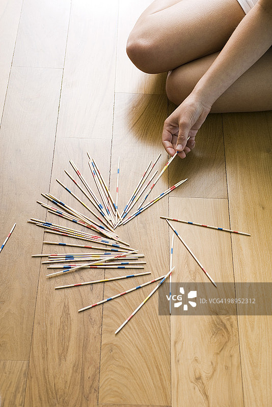 在地上玩挑棍游戏的女人图片素材