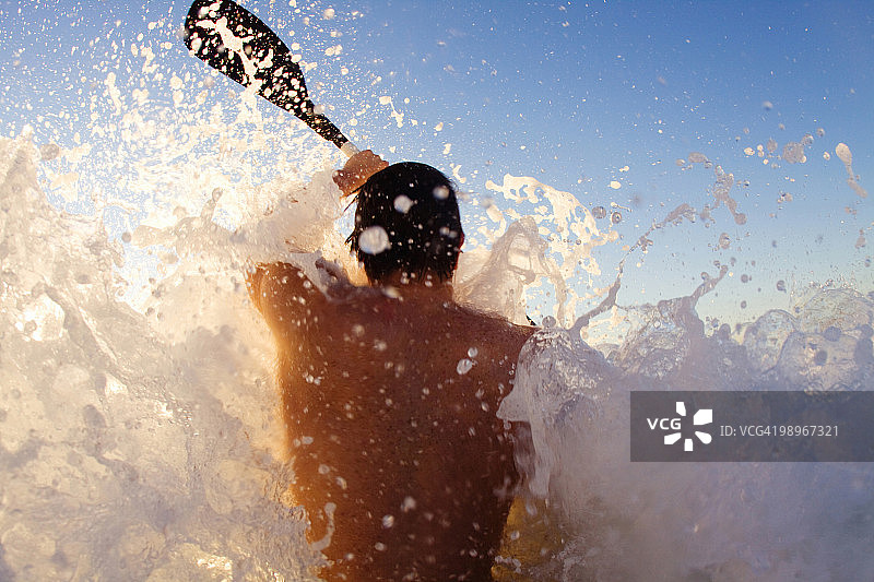 年轻男人在南非夸祖鲁-纳塔尔省德班阳光海岸海浪上划皮划艇图片素材