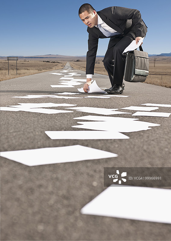 亚洲商人从马路上捡起文件图片素材