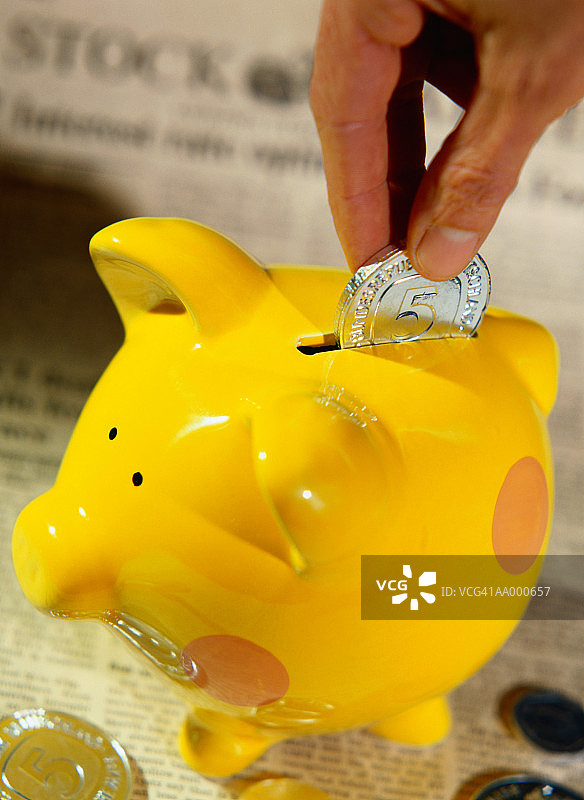 将硬币放入存钱罐的手的特写图片素材