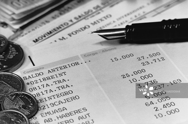 西班牙银行对账单上的钢笔和钱币图片素材