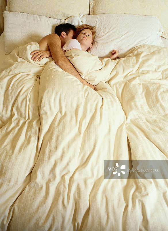 女子醒着躺在熟睡的丈夫旁边图片素材