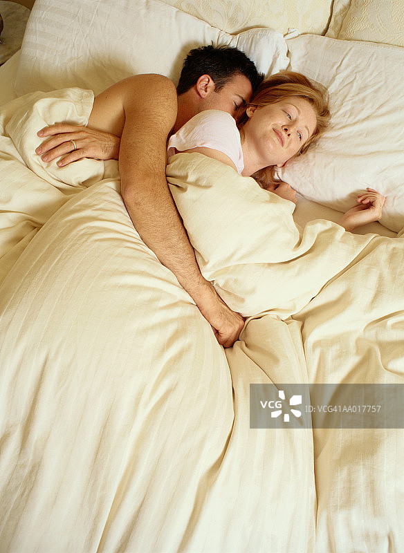 在熟睡丈夫身边的微笑女人图片素材