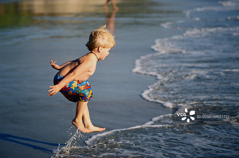 在海浪中玩耍的男孩（2-4岁）侧面视角图片素材