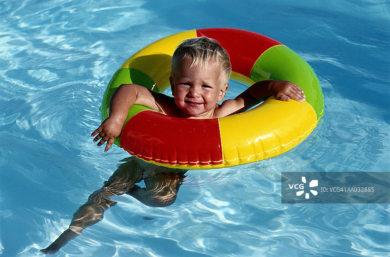 在游泳池里拿着充气游泳圈的小孩图片素材