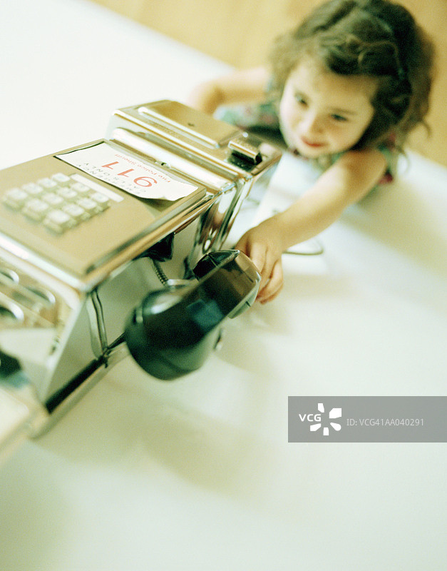够公共电话听筒的女孩（3-5岁），俯视图片素材