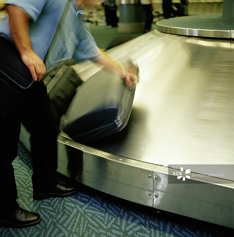 男人从行李认领处取行李，低角度拍摄图片素材