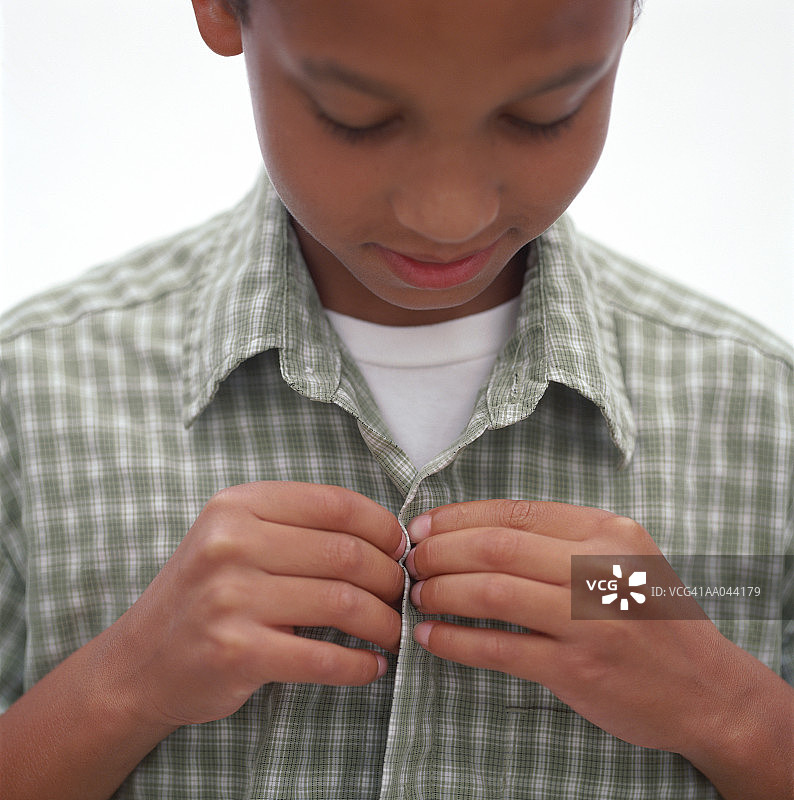 低头扣衬衫的男孩（11-13岁），特写镜头图片素材