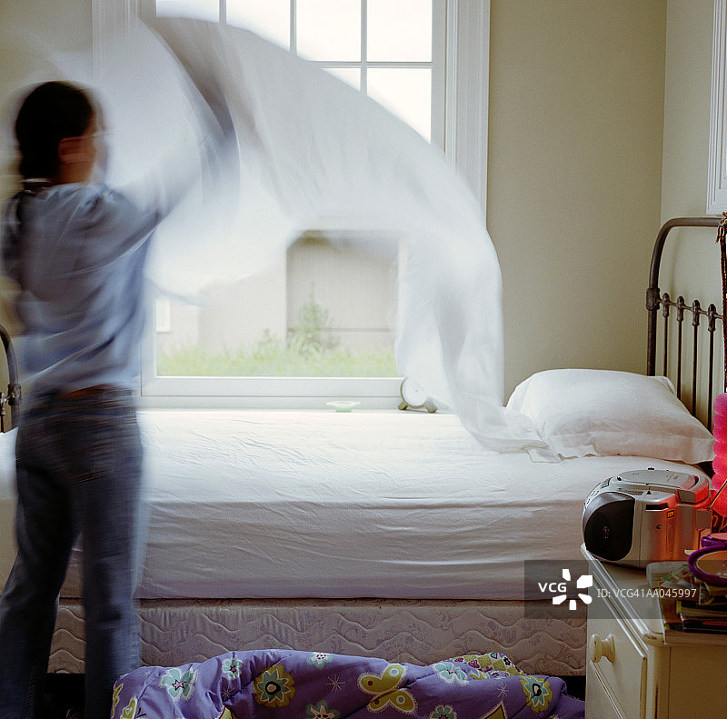 整理床铺的女孩（10-12岁），后视图（动态模糊）图片素材