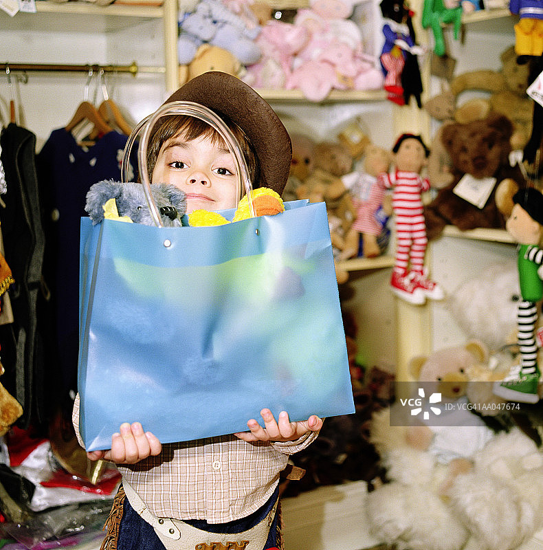 在玩具店拿着购物袋的男孩图片素材
