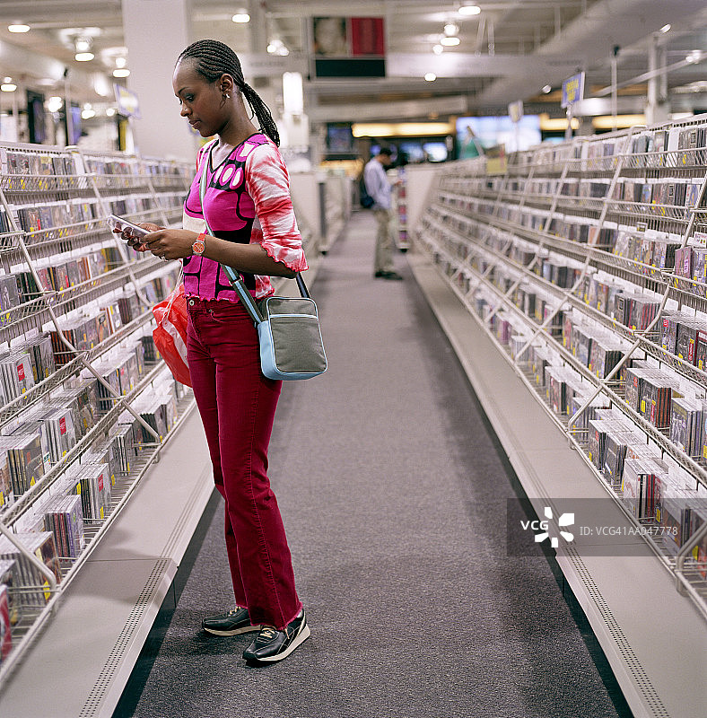 在唱片店购买CD的年轻女人（侧面）图片素材
