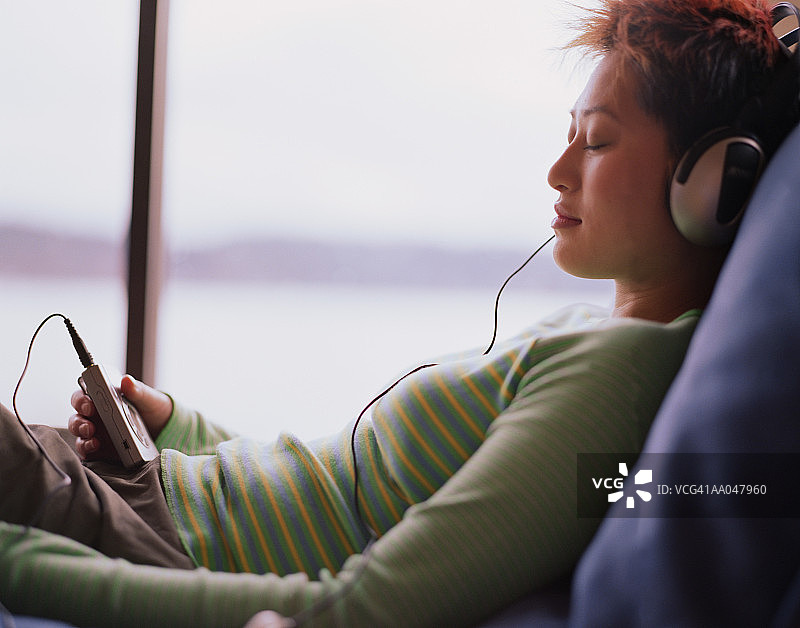 年轻女子闭着眼睛听个人立体声，侧面视角图片素材