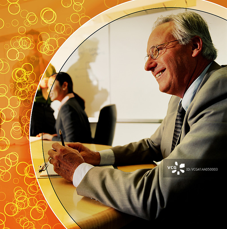 会议桌旁面带微笑的年长的男人（数字合成图）图片素材